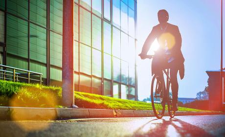 Person riding bicycle next to glass building