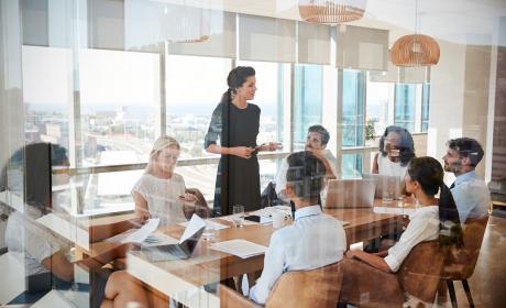Businesswoman leads meeting around table