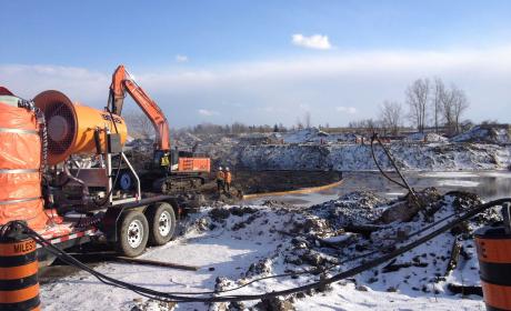 Une excavatrice et un camion remettant en état le sol de la friche industrielle de Brantford par une journée d’hiver ensoleillée