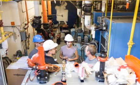 A diverse team of engineers meets in the boiler room of the building